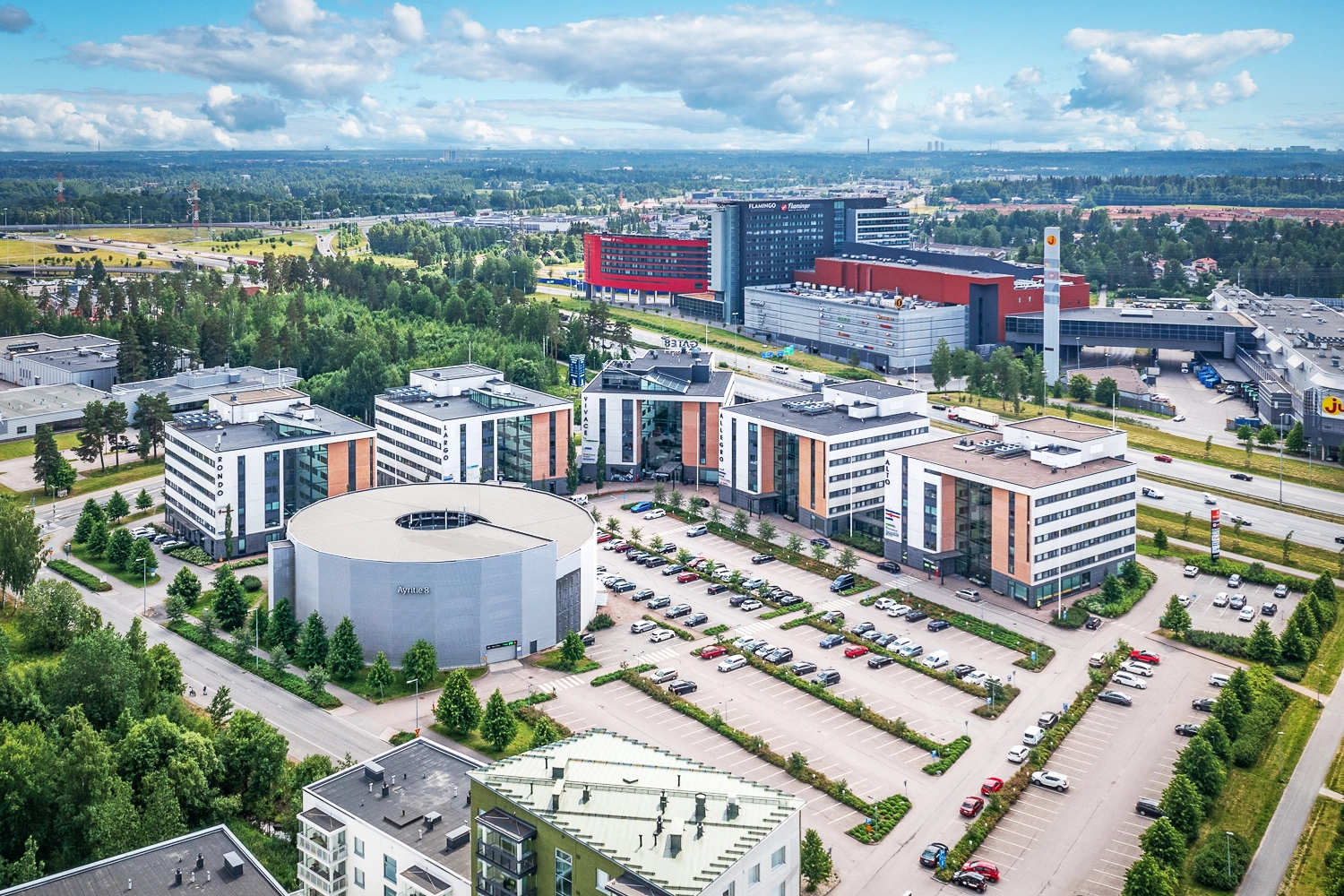 Gate8 Business Parkin useasta rakennuksesta koostuva yrityspuisto ilmasta kuvattuna. Etualalla parkkialue ja pysäköintitalo.