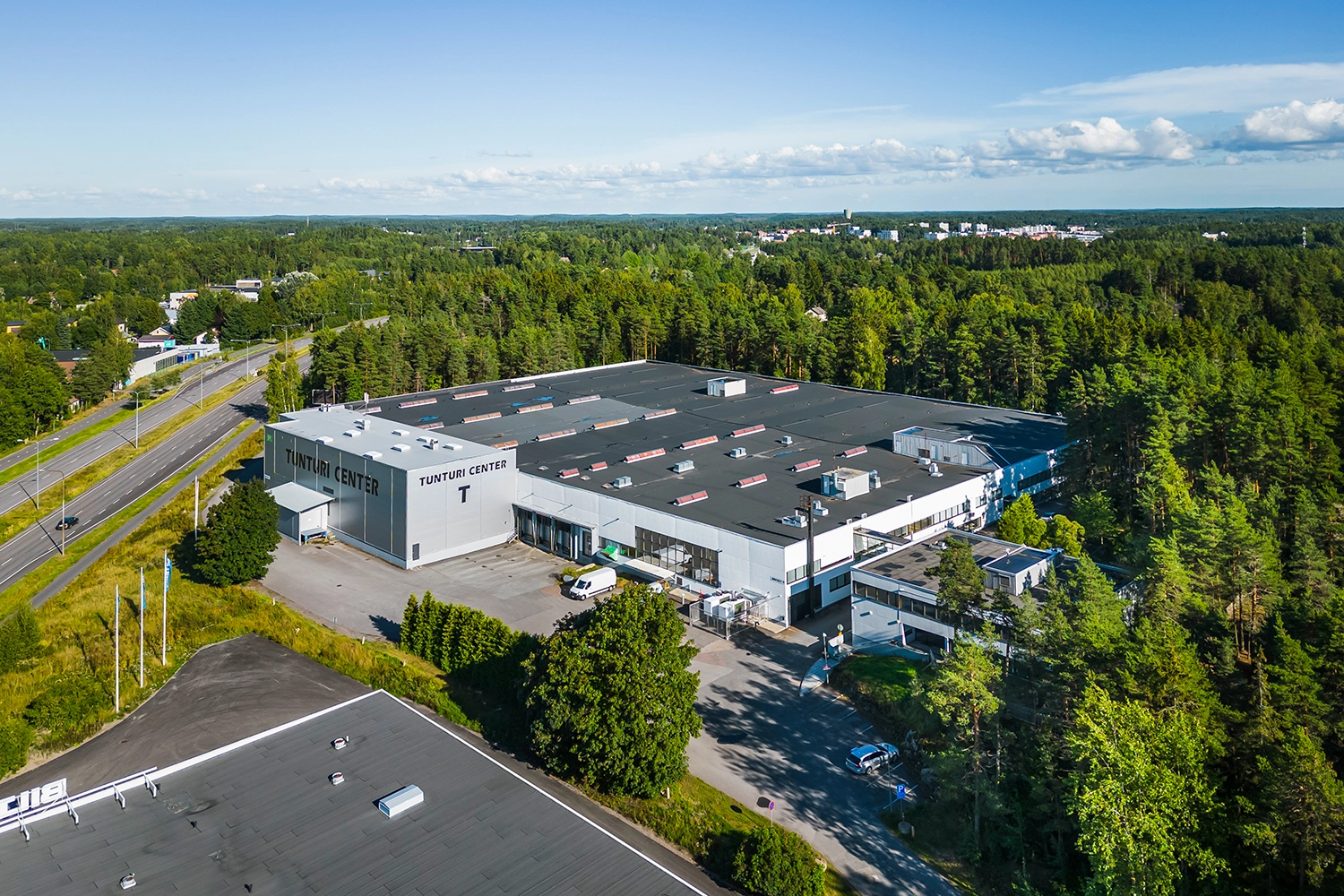 Tunturi Center ilmakuvassa. Suuremmasta tuotanto- ja pienemmästä toimistorakennuksesta koostuva kiinteistö on metsän ympäröimänä suuren tien varressa.