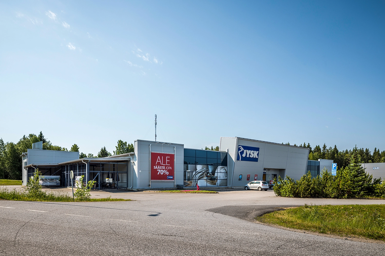 Raahen Jokelantie 5 hillitty julkisivu. Seinässä on huonekaluliikkeen valomainos sekä mainosbanderolli.