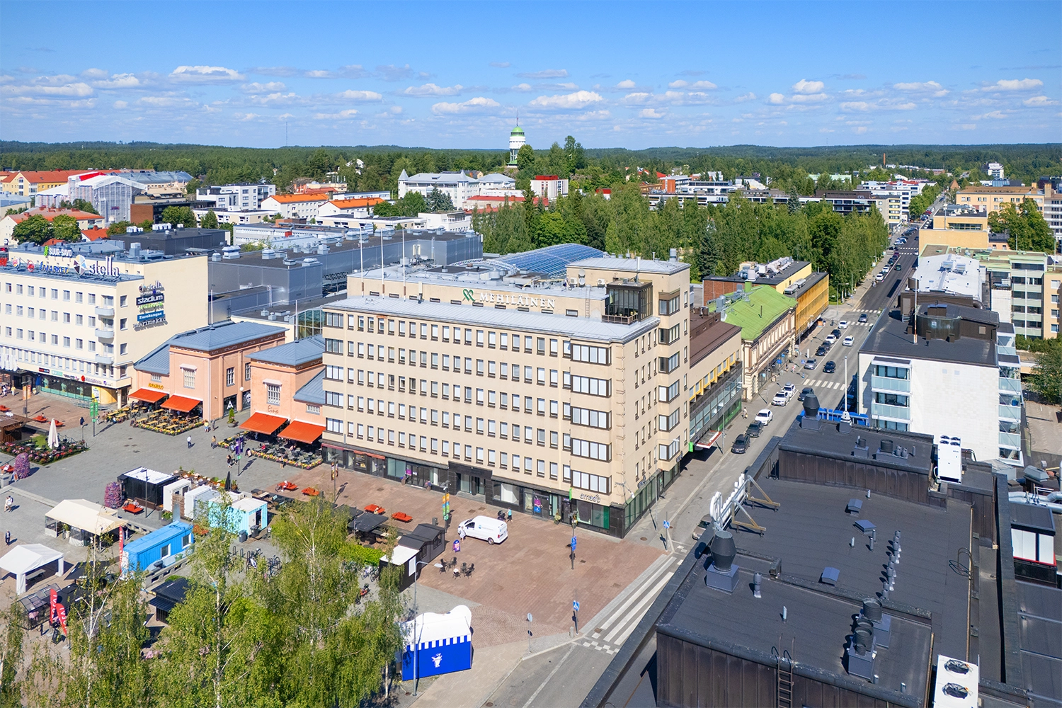 Kuusikerroksinen toimitilakiinteistö, talon edustalla Hallitustori, torikojuja ja kavelykatu.